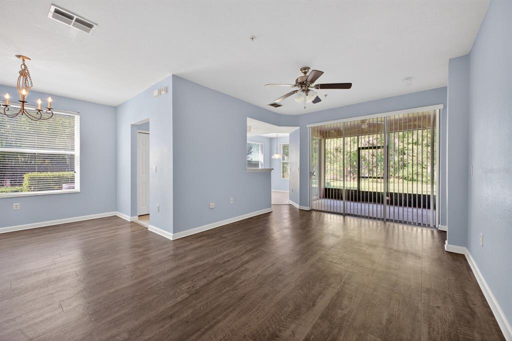An open living area features light blue walls, dark wood-look flooring, and a sliding glass door — 8352 QUIMBY CIRCLE, DAVENPORT, FL