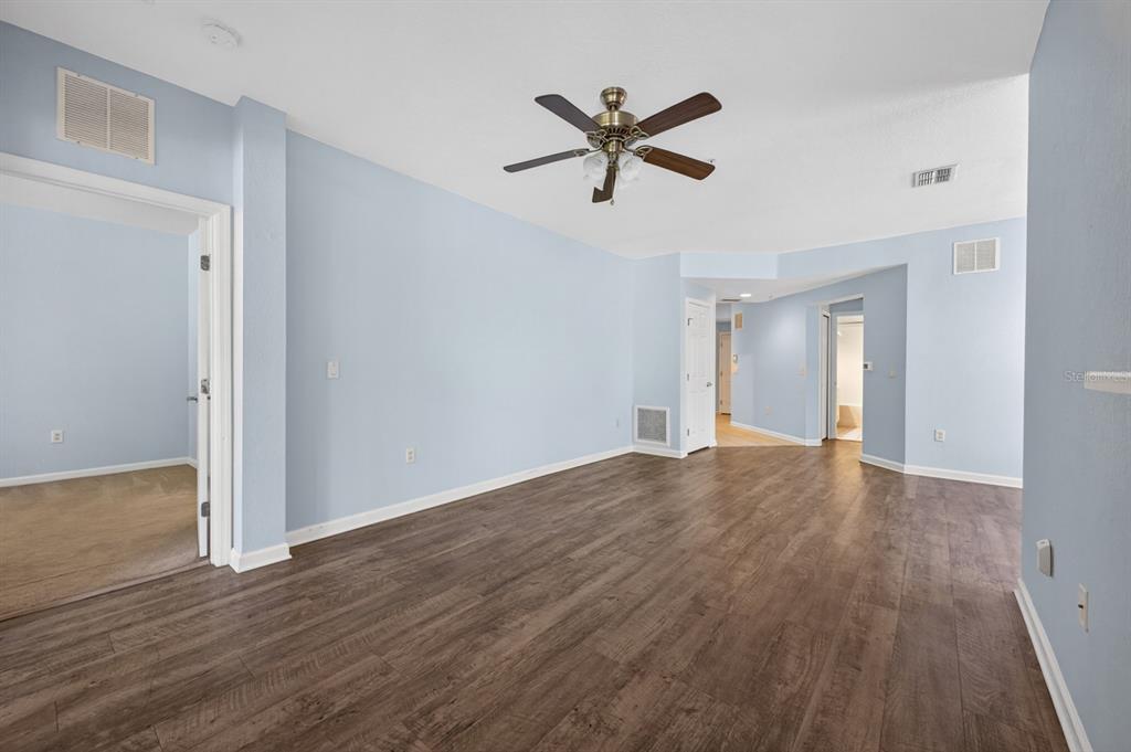 An empty room with light blue walls, dark wood-look flooring, and a ceiling fan — 8352 QUIMBY CIRCLE, DAVENPORT, FL