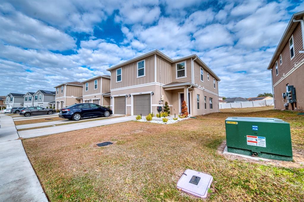 A two-story townhouse with a tan exterior, a two-car garage, and a green utility box — 1568 MIRABELLA CIRCLE, DAVENPORT, FL