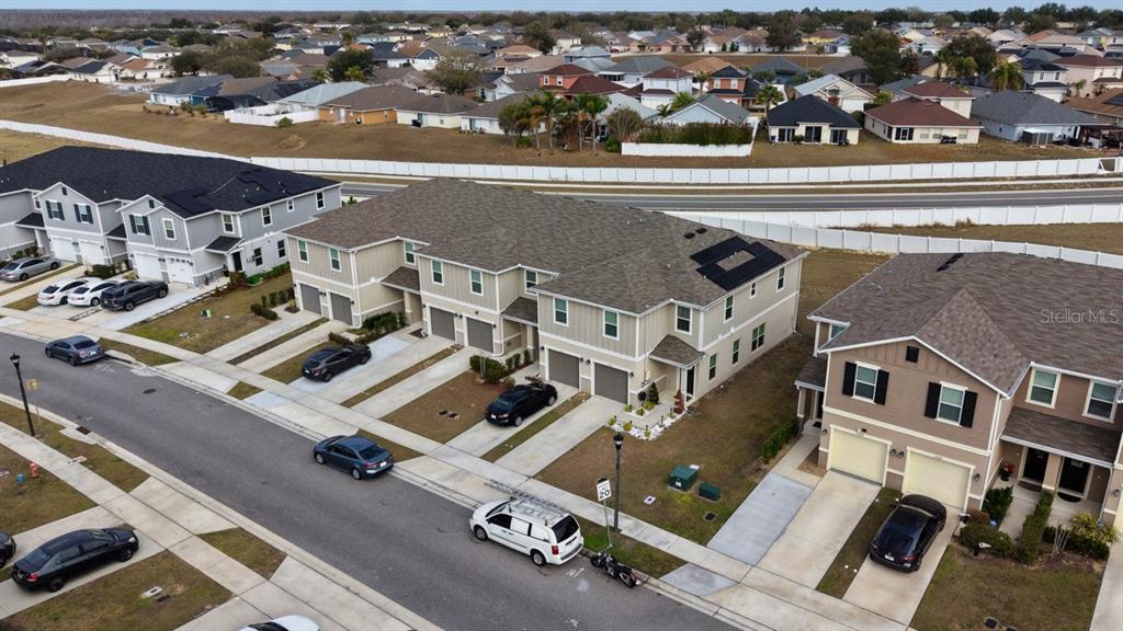 An aerial view shows a multi-unit townhouse complex with attached garages and parked cars — 1568 MIRABELLA CIRCLE, DAVENPORT, FL