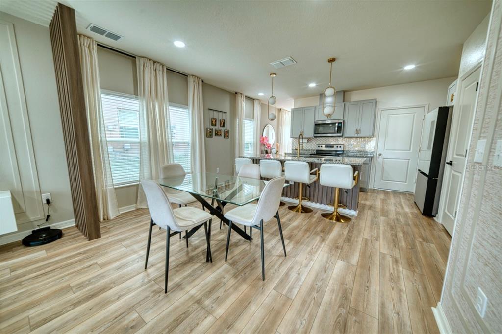 A dining area with a glass table and a kitchen featuring bar seating and cabinetry — 1568 MIRABELLA CIRCLE, DAVENPORT, FL