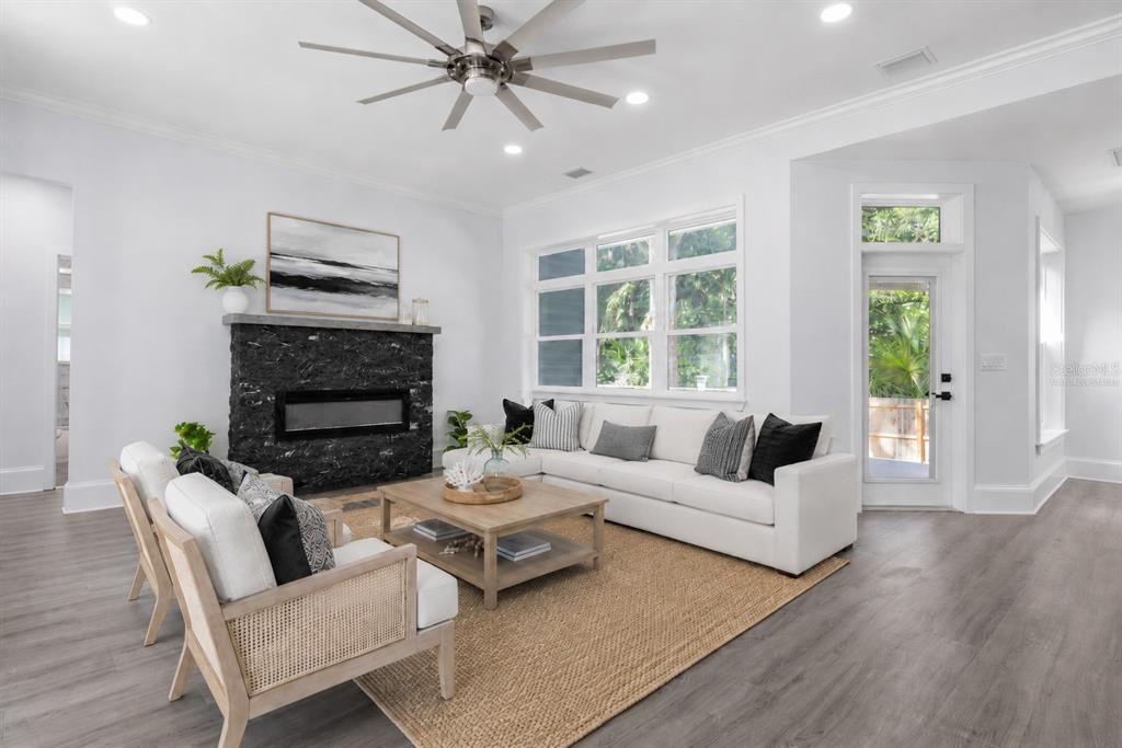 A living room features a black stone fireplace, white sectional sofa, and light wood flooring — 117 HERNANDEZ AVENUE, PALM COAST, FL