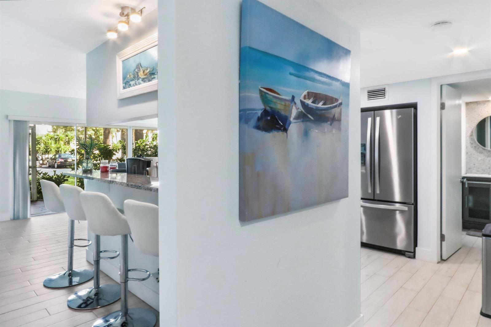 A kitchen breakfast bar with white stools sits beside a wall featuring boat artwork — 1605 S Us Hwy 1, Jupiter FL 33477, JUPITER, FL