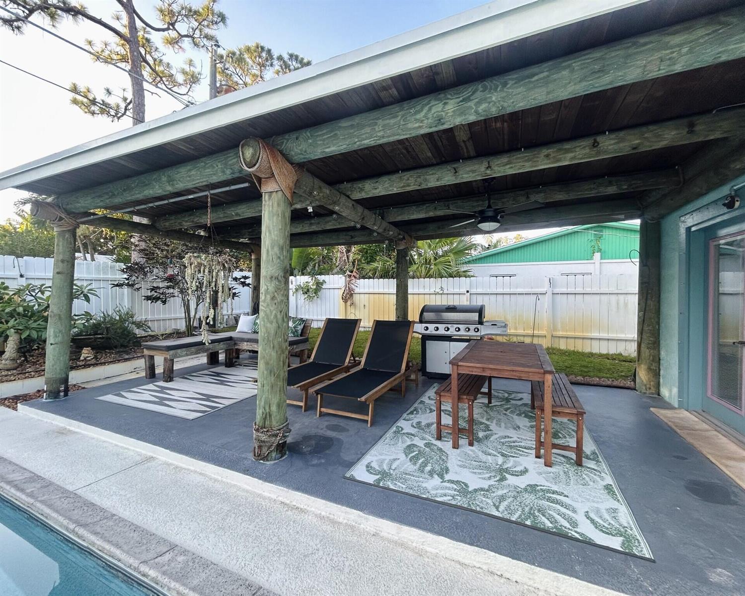 A covered outdoor patio features a dining set, lounge chairs, a grill, and a pool — 1301 SE Sandpiper Lane, Stuart FL 34996, STUART, FL