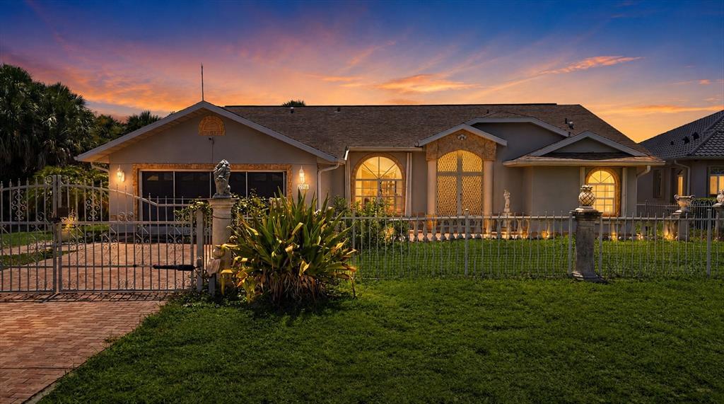 A single-story house with a gated driveway and arched windows at sunset — 126 ORTIZ BOULEVARD, NORTH PORT, FL