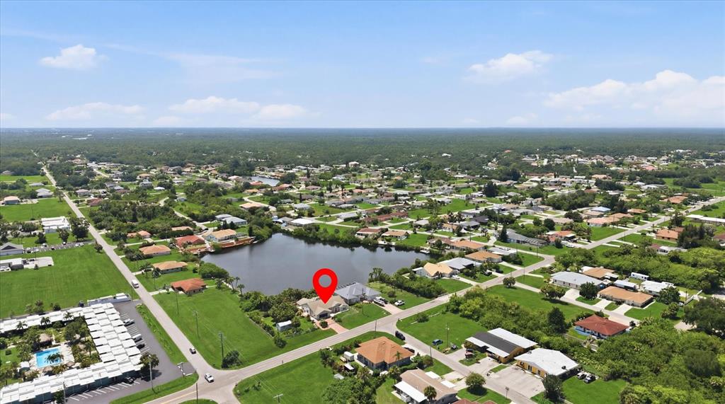 An aerial view shows a house with a red location pin beside a small lake — 126 ORTIZ BOULEVARD, NORTH PORT, FL