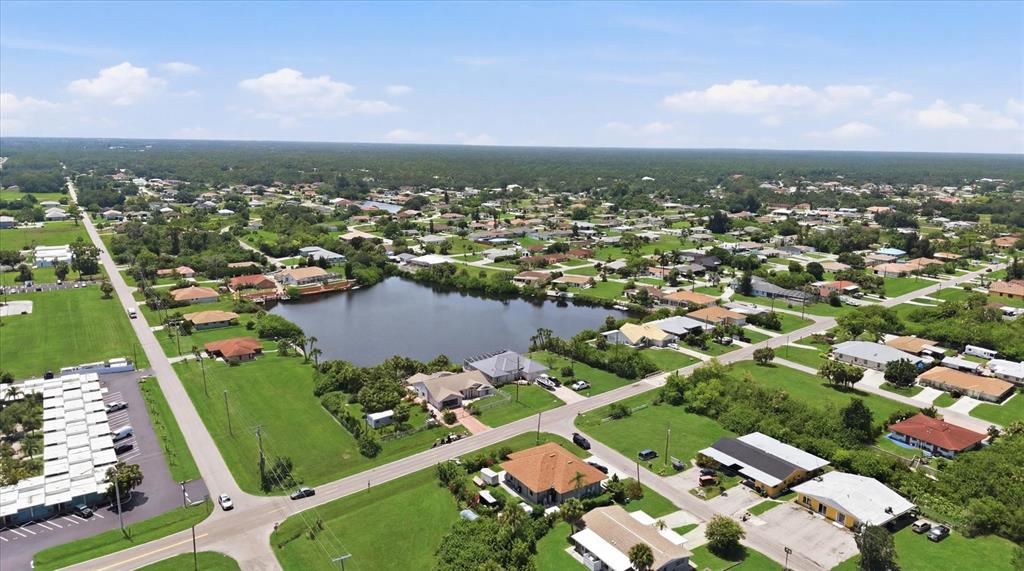 An aerial view shows a suburban neighborhood with a central pond and surrounding residential houses — 126 ORTIZ BOULEVARD, NORTH PORT, FL