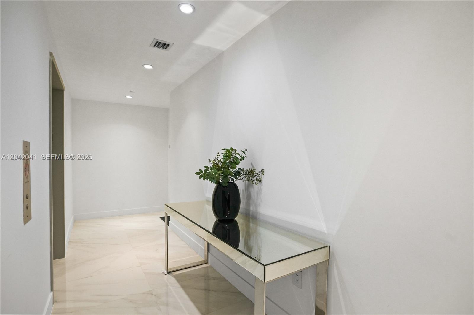 A minimalist hallway features a mirrored console table, a black vase, and recessed ceiling lighting — 700 NE 24 # 3905, Miami FL 33137, MIAMI, FL