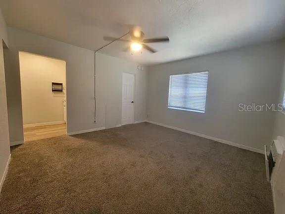 A carpeted room with a ceiling fan, a window with blinds, and an open doorway — 820 8TH AVENUE S UNIT E, ST PETERSBURG, FL
