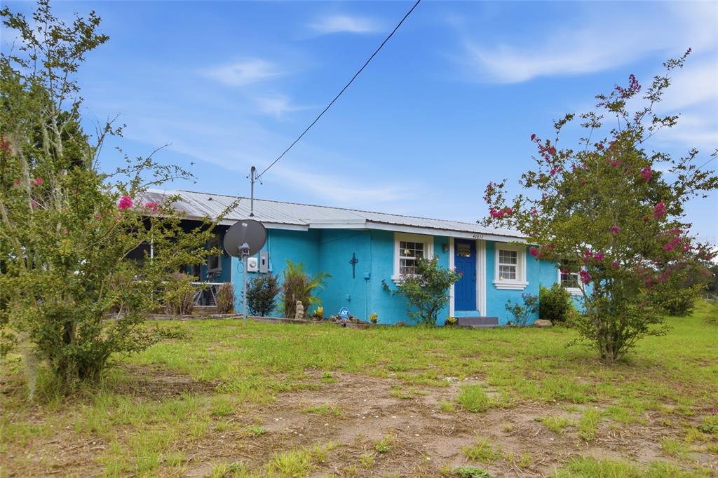 A bright blue single-story house with a metal roof sits on a grassy lot — 40832 RIVER ROAD, DADE CITY, FL
