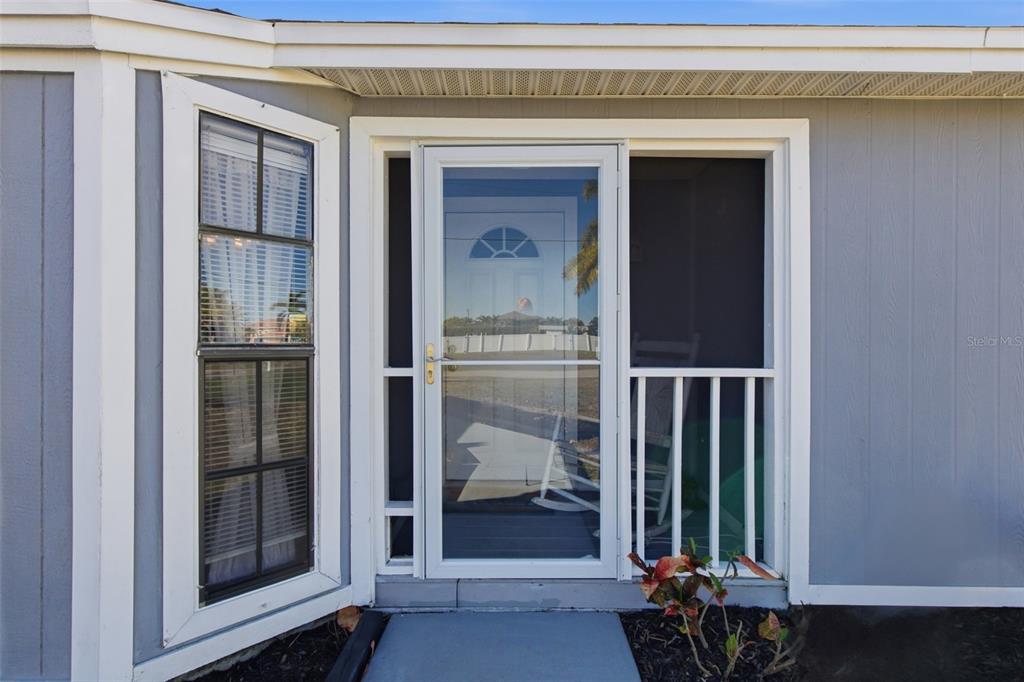 A white storm door and a window with shutters on a gray exterior wall — 3706 NW 1ST TERRACE, CAPE CORAL, FL