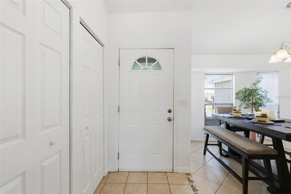 An entryway with tiled floors, white closet doors, and a front door leads to a dining area — 3706 NW 1ST TERRACE, CAPE CORAL, FL
