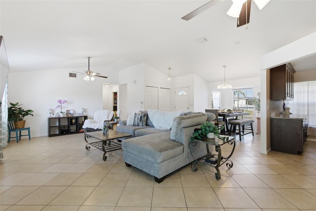 A spacious living room features tile flooring, a gray sectional sofa, and an open layout — 3706 NW 1ST TERRACE, CAPE CORAL, FL