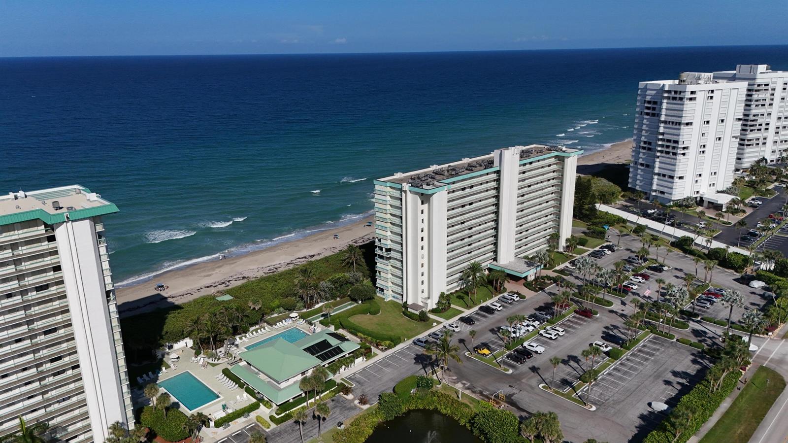 An aerial view shows high-rise beachfront condominiums with swimming pools and a parking lot — 9940 S Ocean Drive # 1005, Jensen Beach FL 34957, JENSEN BEACH, FL