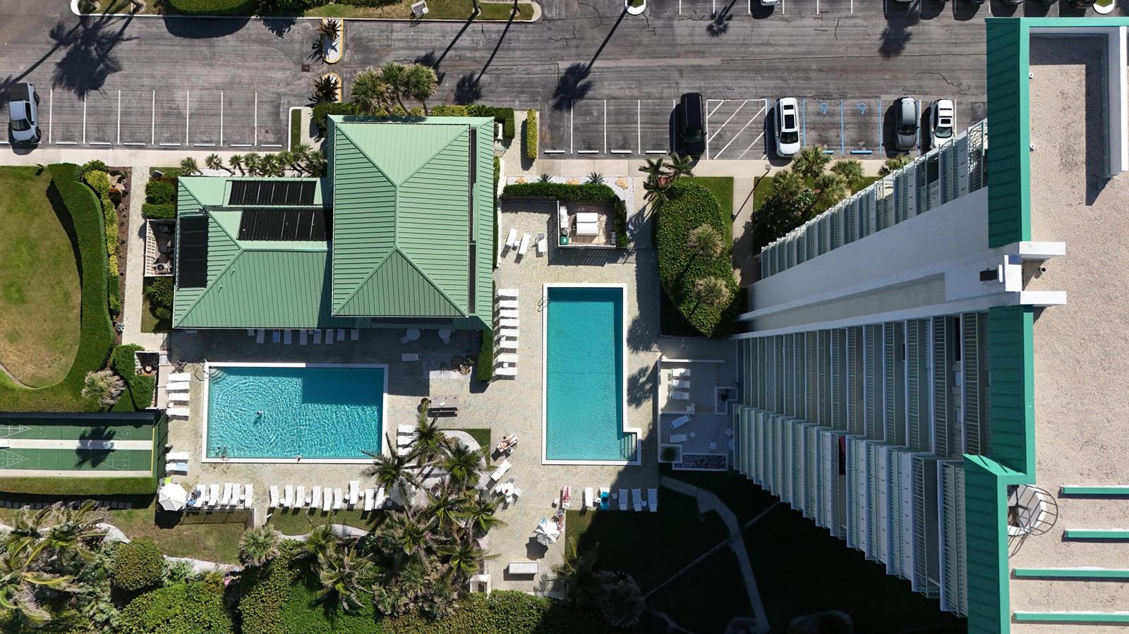 An aerial view shows a high-rise building, two swimming pools, and a green-roofed clubhouse — 9940 S Ocean Drive # 1005, Jensen Beach FL 34957, JENSEN BEACH, FL