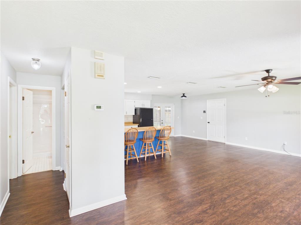 A living area with dark wood flooring features a kitchen island with blue bar stools — 6155 NW 58TH TERRACE, OCALA, FL