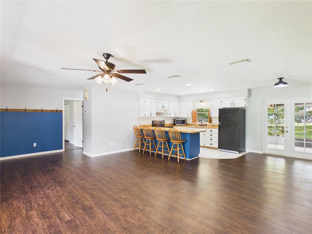 An open-concept kitchen with a blue island and bar stools overlooks a large living area — 6155 NW 58TH TERRACE, OCALA, FL
