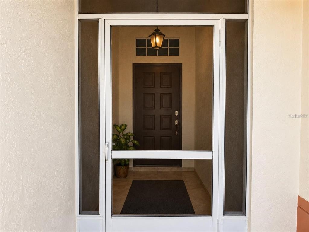 A white storm door with a screen opens to a covered entryway with a dark door — 822 MCCALLISTER UNIT 822, SUN CITY CENTER, FL