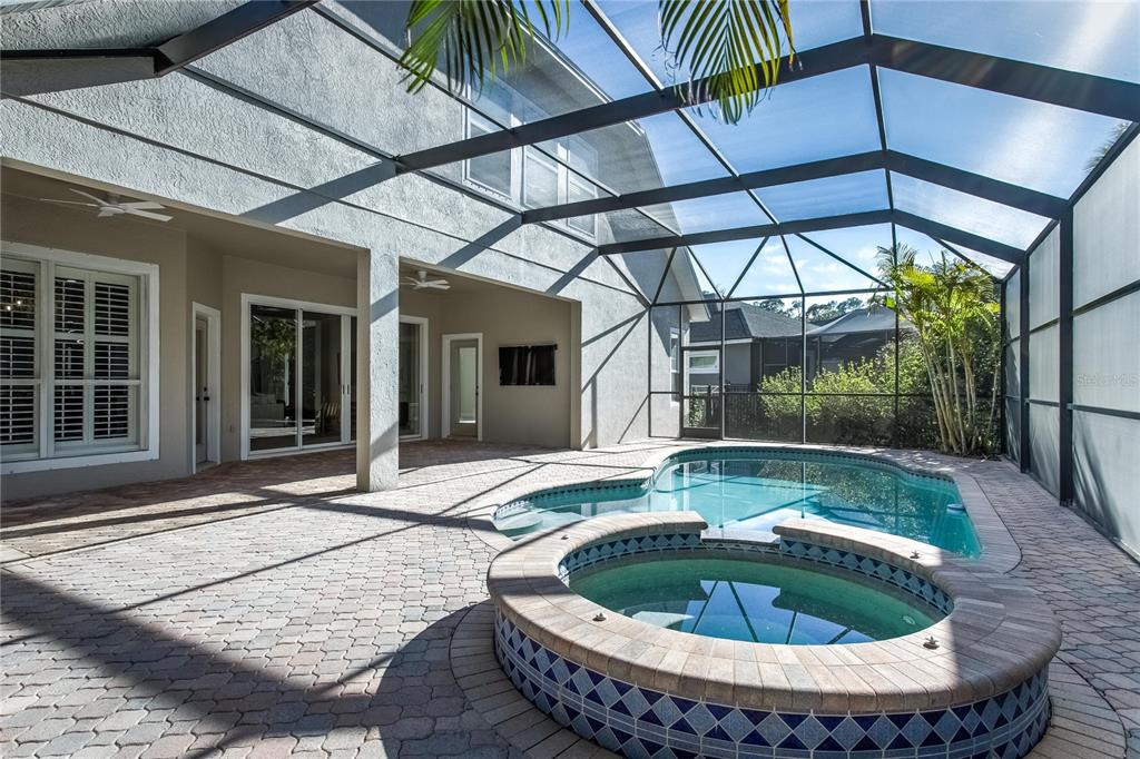 A screened-in patio features a swimming pool, a raised hot tub, and paver flooring — 11909 MANDEVILLA COURT, TAMPA, FL