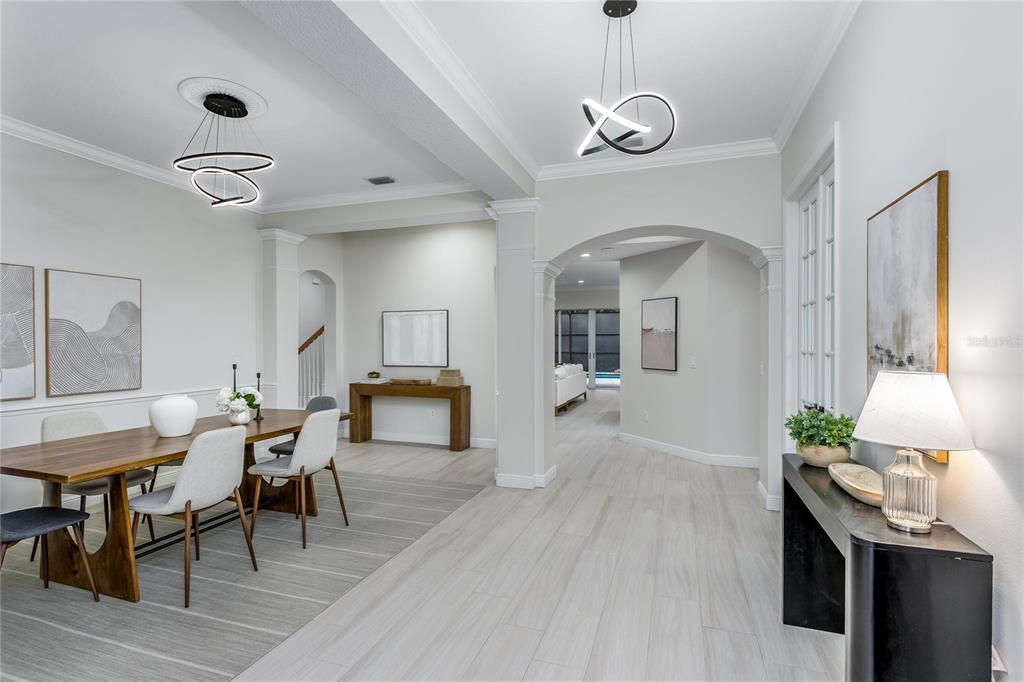 A dining area with a wooden table and modern lighting leads into a bright hallway — 11909 MANDEVILLA COURT, TAMPA, FL