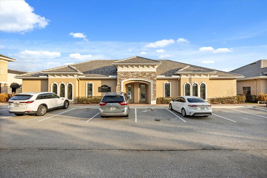 A single-story commercial building with a stone-accented entrance and a parking lot in front — 4347 HUNTERS PARK LANE UNIT 102, ORLANDO, FL