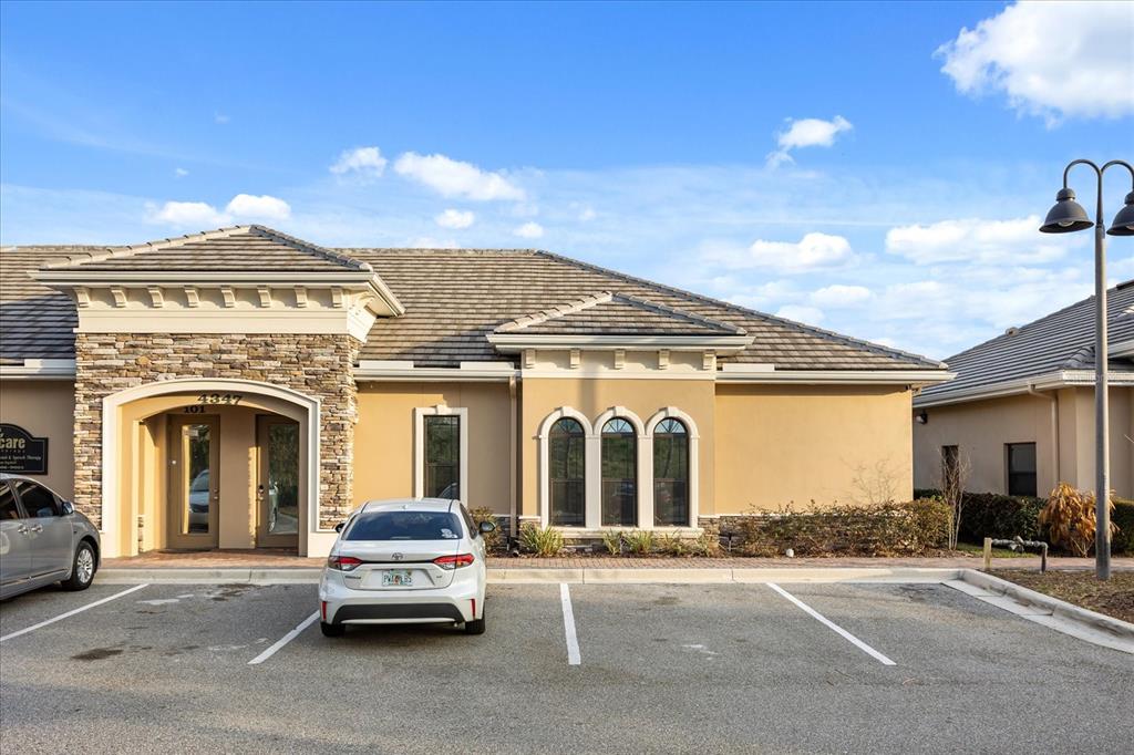 A single-story commercial building with a stone facade entrance and a paved parking lot — 4347 HUNTERS PARK LANE UNIT 102, ORLANDO, FL