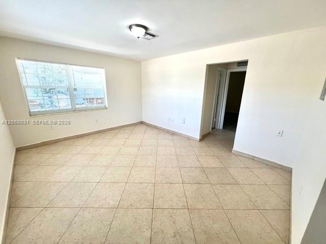An empty room features light-colored tile flooring, white walls, and a window with blinds — 696 NE 85th St # 1, Miami FL 33138, MIAMI, FL