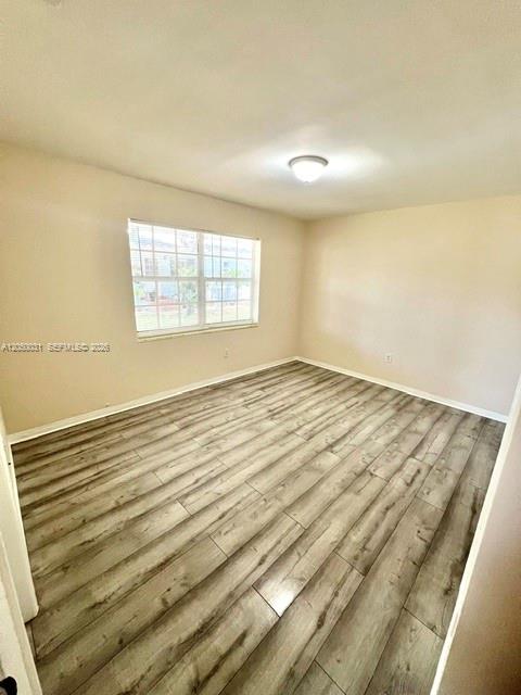 An empty bedroom features light-colored walls, a single window, and wood-look laminate flooring — 696 NE 85th St # 1, Miami FL 33138, MIAMI, FL