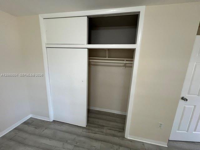 A closet with white sliding doors and an open upper storage shelf in a room — 696 NE 85th St # 1, Miami FL 33138, MIAMI, FL