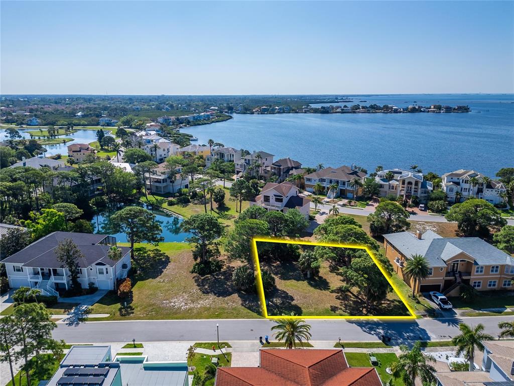 An aerial view shows a vacant, rectangular residential lot outlined in yellow near a waterfront — HARBOUR WATCH CIRCLE, TARPON SPRINGS, FL