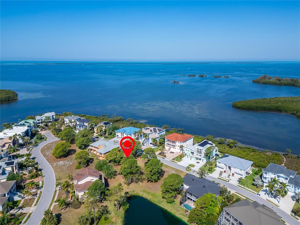 An aerial view shows a coastal residential neighborhood with a red marker on a lot — HARBOUR WATCH CIRCLE, TARPON SPRINGS, FL