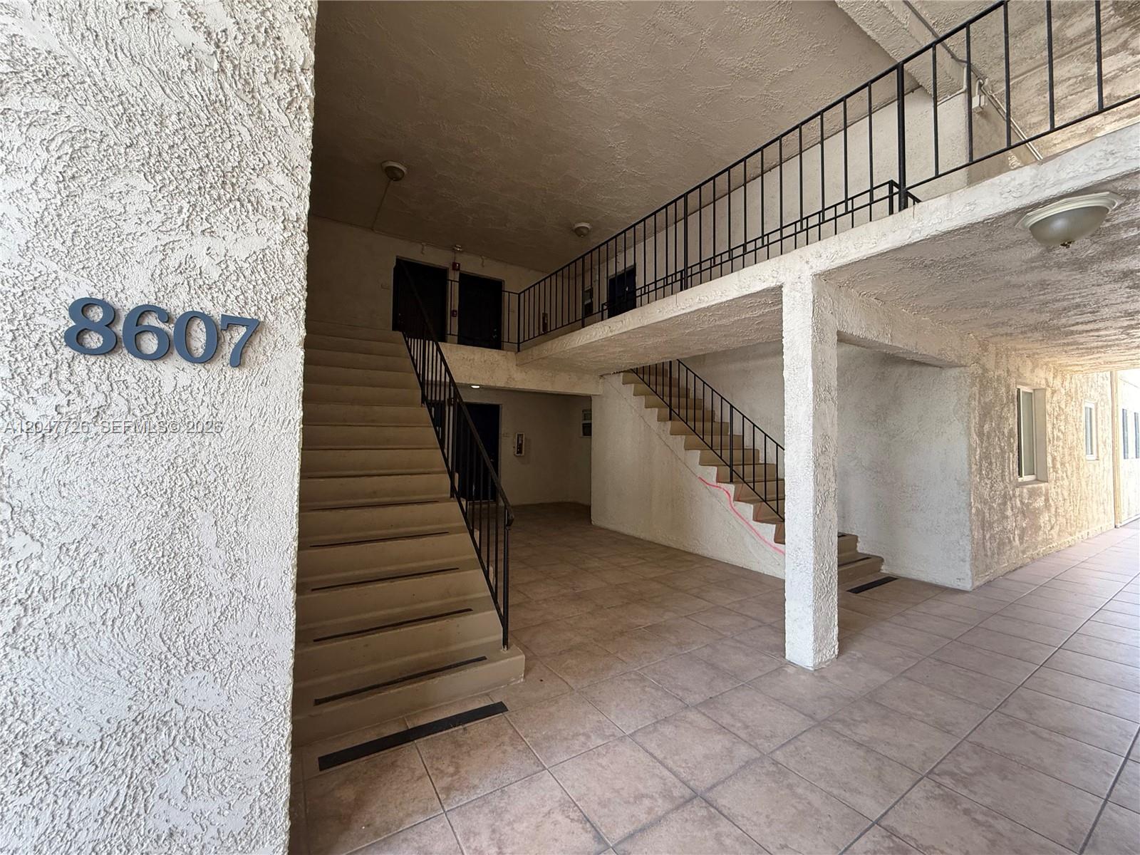 An exterior view shows a two-story building entrance with concrete stairs and metal railings — 8607 SW 68th Ct # 24, Pinecrest FL 33156, PINECREST, FL