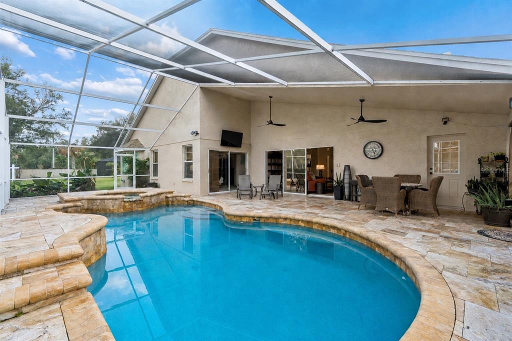 A screened-in patio features a swimming pool, a hot tub, and outdoor seating — 17503 EDINBURGH DRIVE, TAMPA, FL
