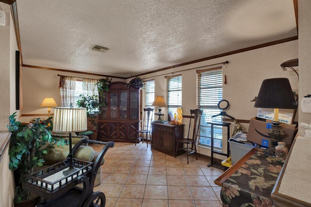 A living room features tile flooring, multiple windows with blinds, and traditional wooden furniture — 12030 106TH COURT, LARGO, FL