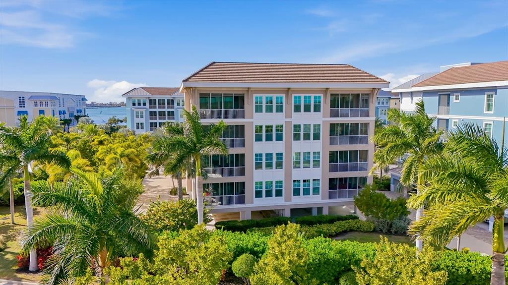 An aerial view shows two multi-story apartment buildings surrounded by palm trees and a lake — 395 ARUBA CIRCLE UNIT 303, BRADENTON, FL
