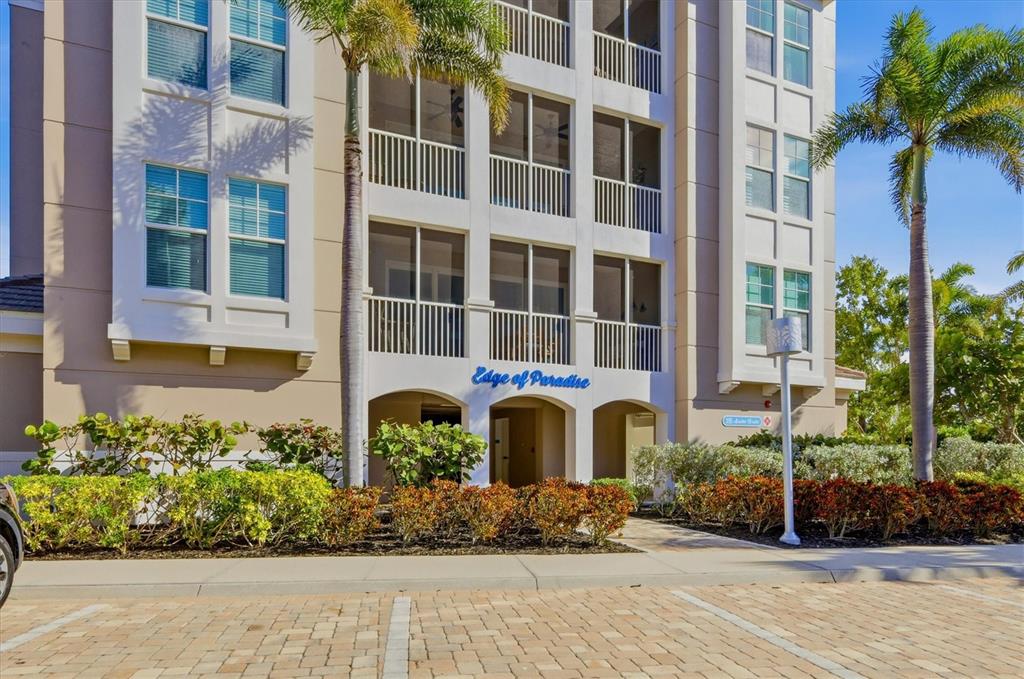 The exterior of a multi-story residential building features a screened entrance labeled Edge of Paradise — 395 ARUBA CIRCLE UNIT 303, BRADENTON, FL