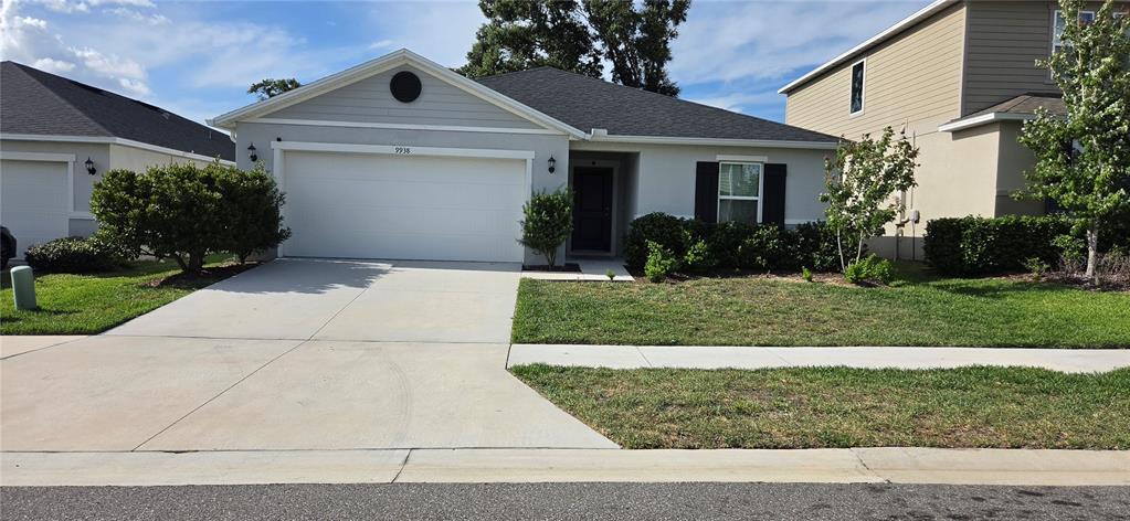 A single-story house with a two-car garage and a front lawn under a blue sky — 9938 MESIC WOODS AVENUE, SEFFNER, FL
