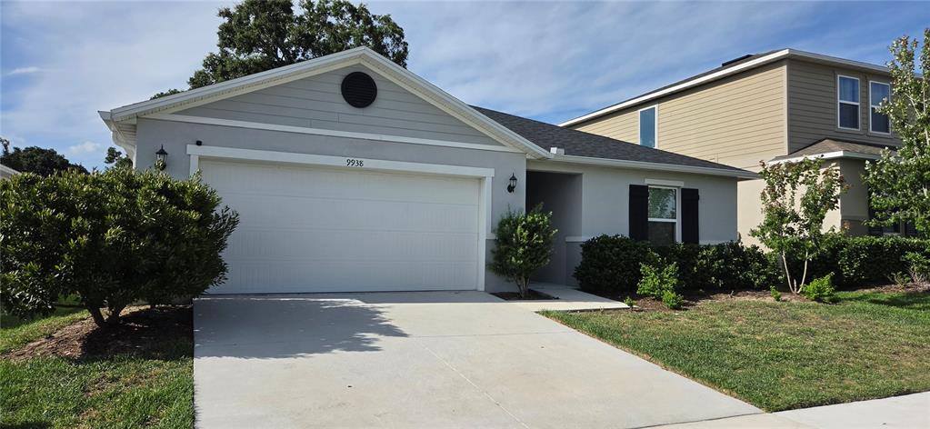 A single-story house with a white garage, gray siding, and a concrete driveway — 9938 MESIC WOODS AVENUE, SEFFNER, FL