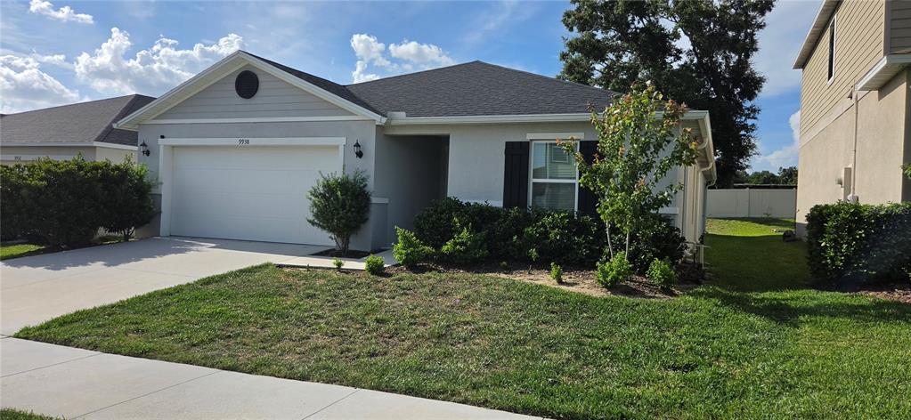 A single-story house with a white garage, gray siding, and a landscaped front yard — 9938 MESIC WOODS AVENUE, SEFFNER, FL