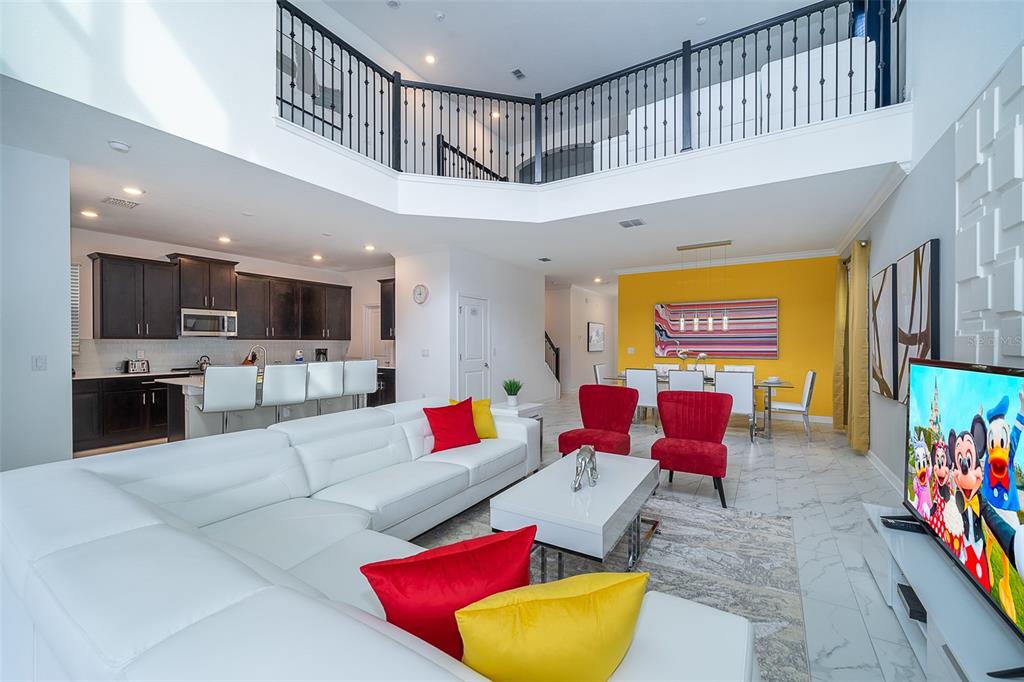 A spacious open-concept living area features a white sectional sofa, kitchen, and dining space — 4156 PARAGRAPH DRIVE, KISSIMMEE, FL