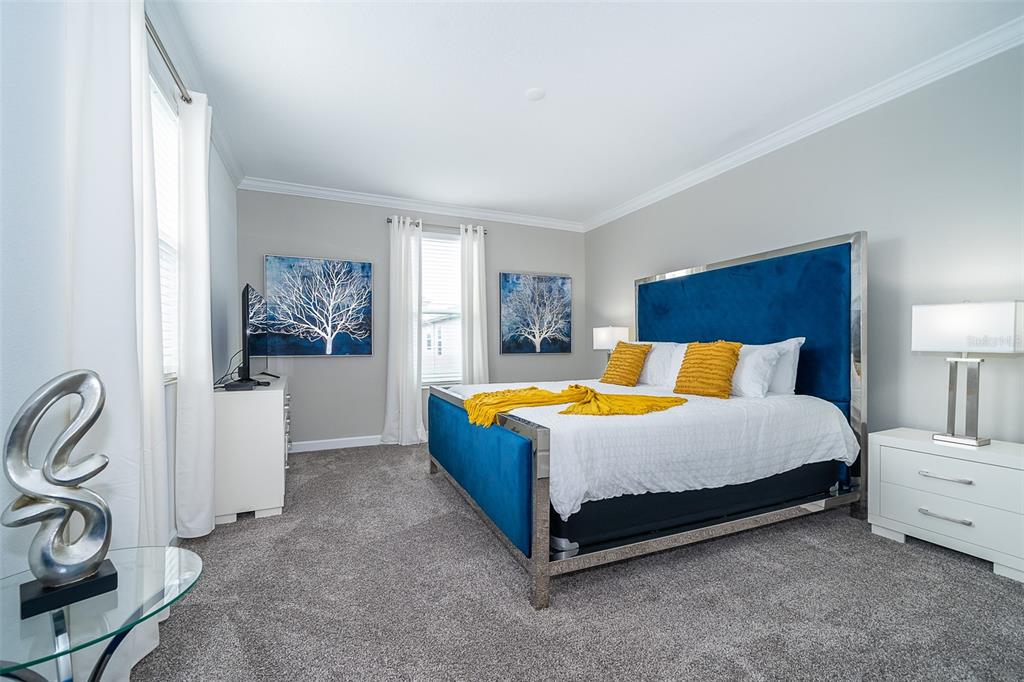 A bedroom features a blue velvet bed frame, gray carpeting, and two tree-themed wall art pieces — 4156 PARAGRAPH DRIVE, KISSIMMEE, FL