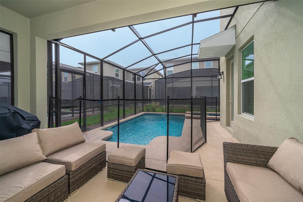 A screened-in patio features a small swimming pool, outdoor furniture, and a safety fence — 4156 PARAGRAPH DRIVE, KISSIMMEE, FL