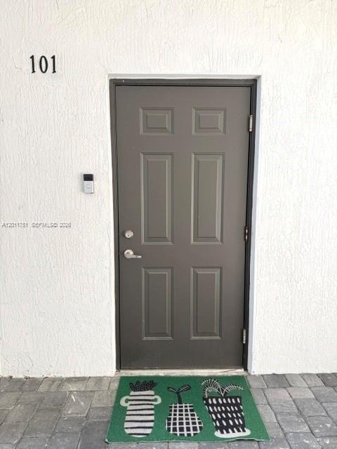 A dark gray front door with a doorbell camera and a patterned green welcome mat — 15650 SW 136th St # 101, Miami FL 33196, MIAMI, FL