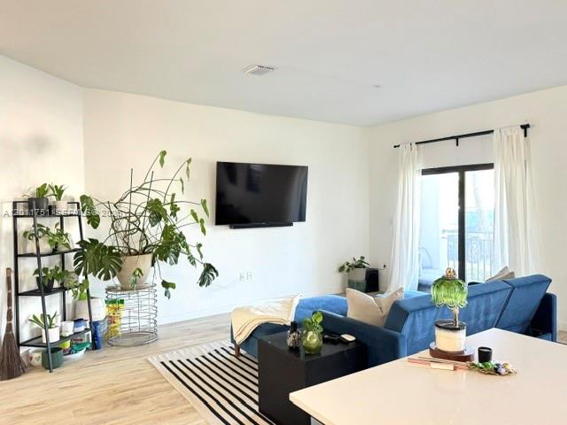 A living room features a blue sofa, a wall-mounted television, and a tall plant stand — 15650 SW 136th St # 101, Miami FL 33196, MIAMI, FL