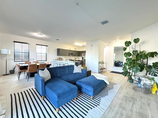 A modern open-concept living room features a blue sectional sofa and an adjacent dining area — 15650 SW 136th St # 101, Miami FL 33196, MIAMI, FL