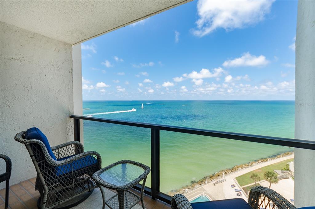 A balcony with wicker furniture overlooks the ocean under a clear blue sky — 450 S GULFVIEW BOULEVARD UNIT 1204, CLEARWATER, FL