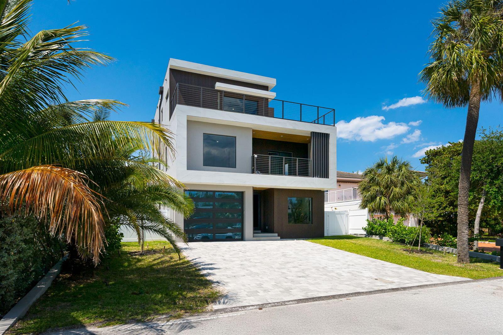A modern three-story house with a paved driveway, balconies, and palm trees under a blue sky — 3225 Canal Drive, Pompano Beach FL 33062, POMPANO BEACH, FL