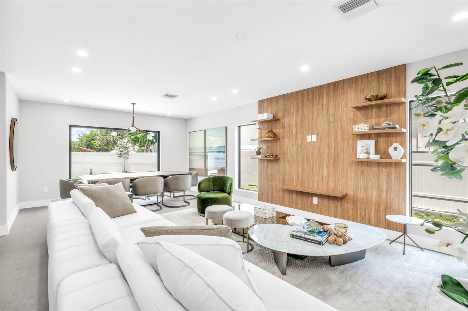 A modern living and dining area features a wood-paneled accent wall and white sectional sofa — 3225 Canal Drive, Pompano Beach FL 33062, POMPANO BEACH, FL
