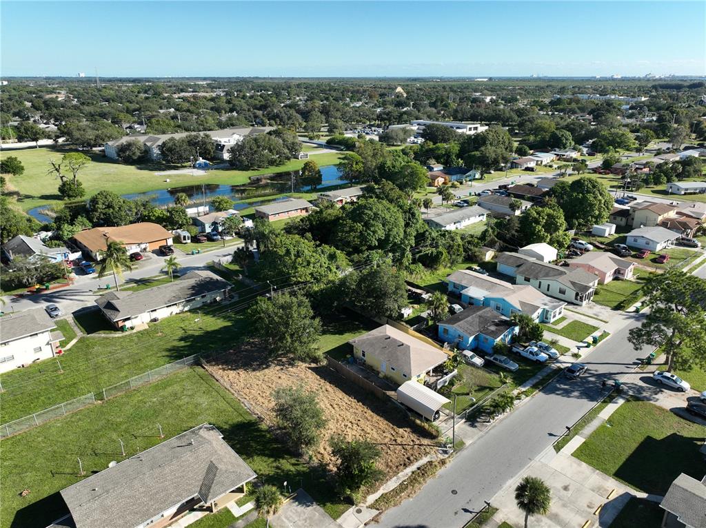 An aerial view shows a residential neighborhood with houses, a vacant lot, and a pond — 478 ROOSEVELT AVENUE, MERRITT ISLAND, FL