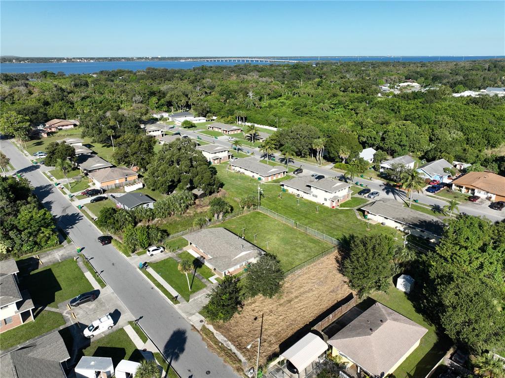 An aerial view shows a residential neighborhood with houses, streets, and a distant bridge — 478 ROOSEVELT AVENUE, MERRITT ISLAND, FL
